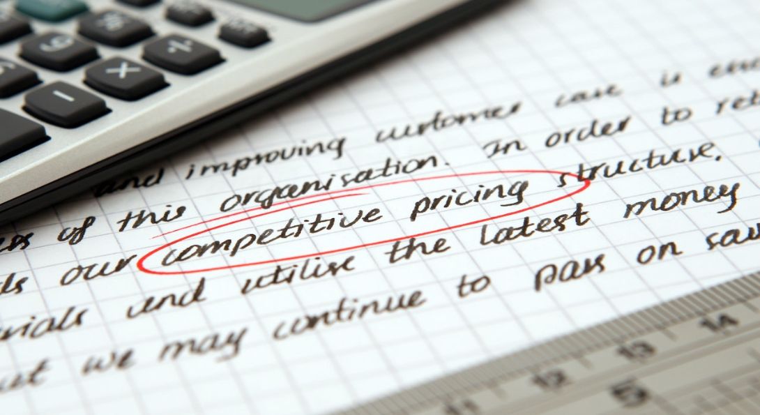 Calculadora sobre um caderno de anotações com a expressão preços compretitivos